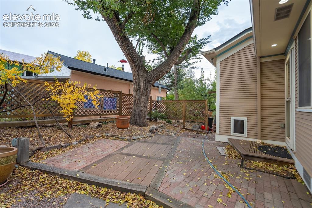Image 32 of 40: Paved patio area with brick and wood-finish sections, bordered by a wooden