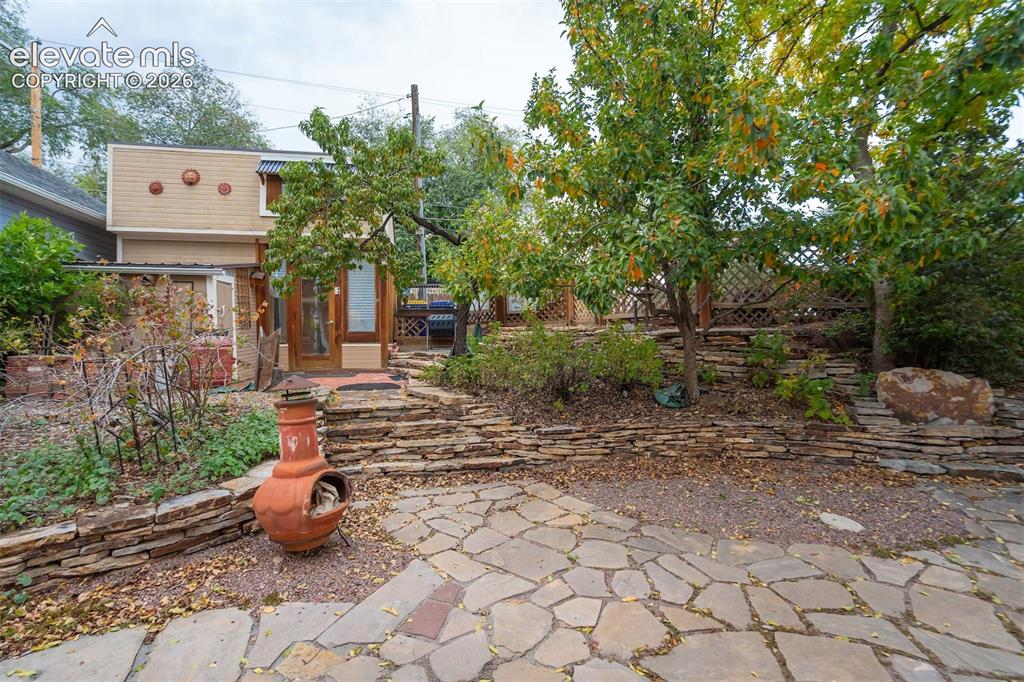 Image 40 of 40: Stone paver patio leading to natural stone steps with stacked stone retaini