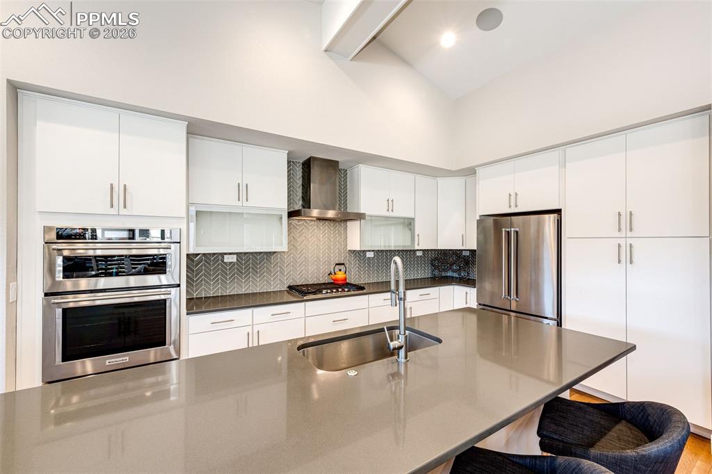 Image 11 of 47: Custom glass front open cabinetry, Herringbone backsplash, and Gourmet Styl