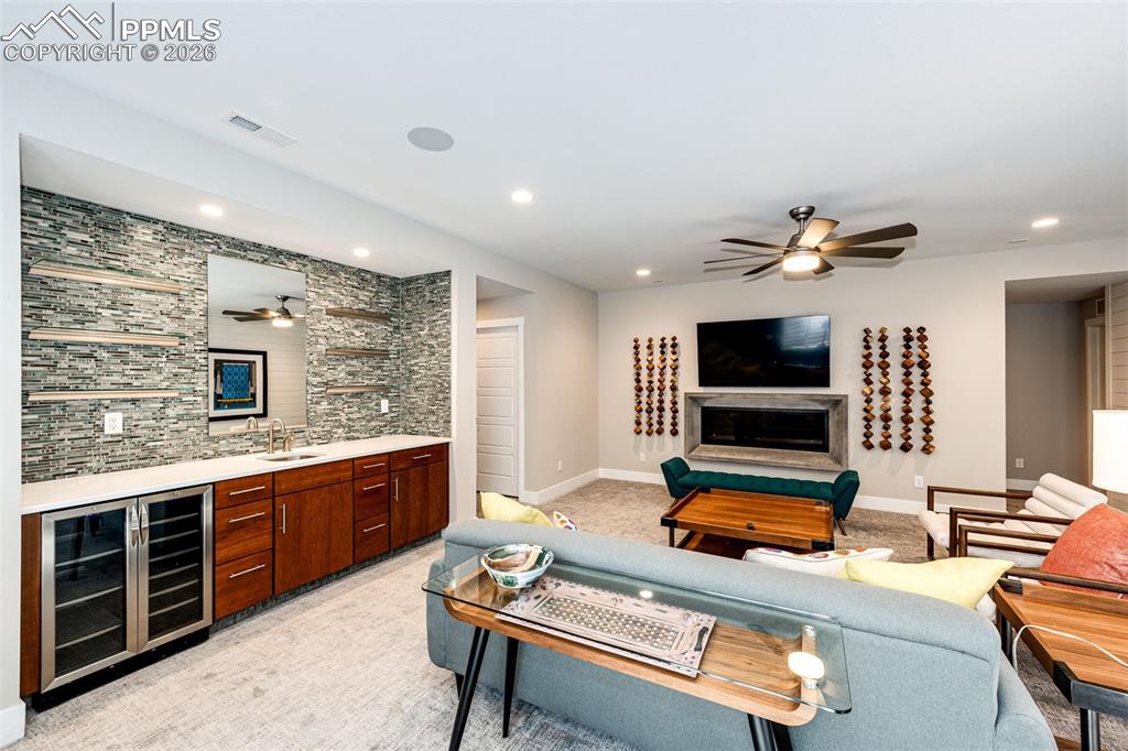 Image 24 of 46: Downstairs Rec Room wet bar with beverage refrigerators and fireplace. Reme