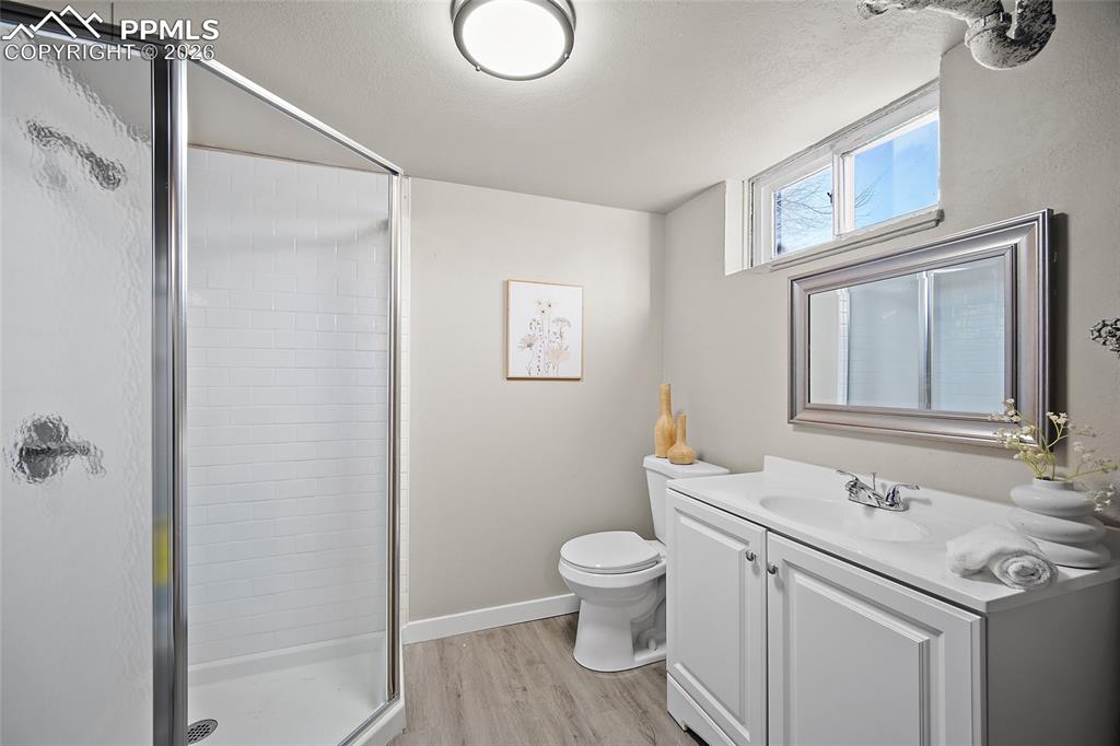 Image 15 of 29: Full bathroom featuring a shower stall, vanity, light wood-style floors, an