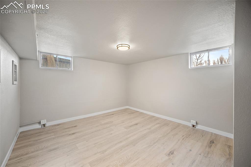 Image 18 of 29: Below grade area featuring a textured ceiling and light wood-type flooring