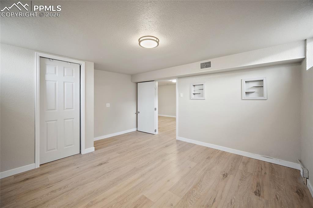Image 19 of 29: Finished below grade area with a textured ceiling and light wood-style floo