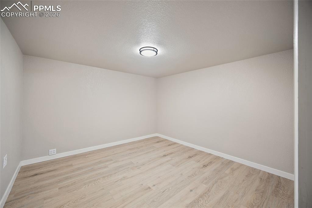 Image 20 of 29: Empty room featuring light wood-style floors and a textured ceiling