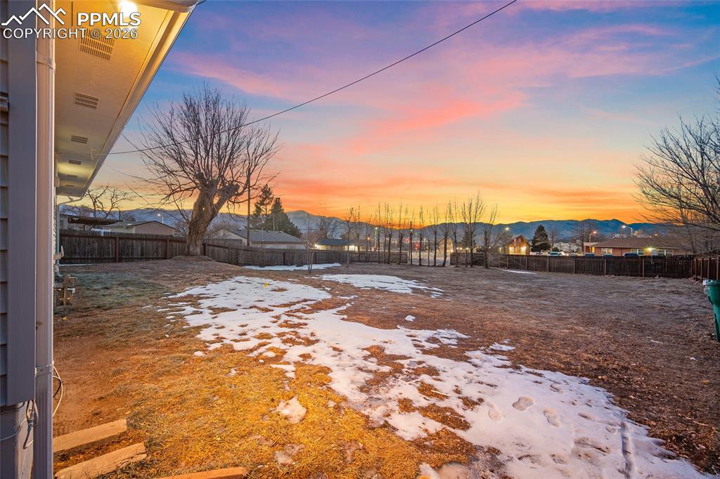 Image 25 of 29: Yard layered in snow featuring a fenced backyard and a mountain view