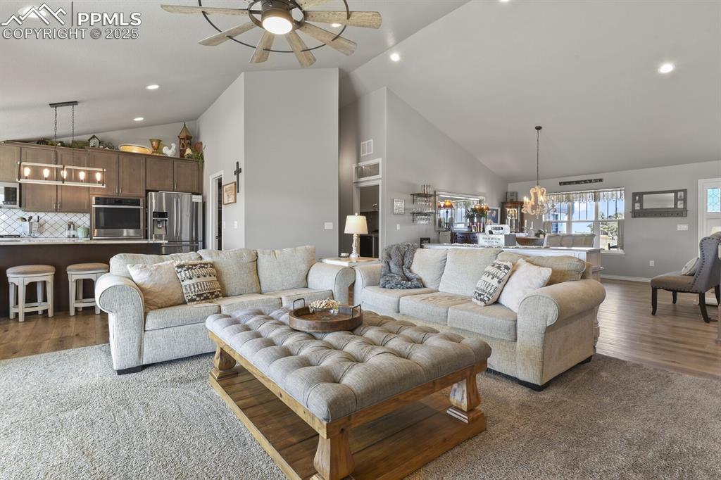 Image 10 of 49: Living room with high vaulted ceiling, ceiling fan with notable chandelier,