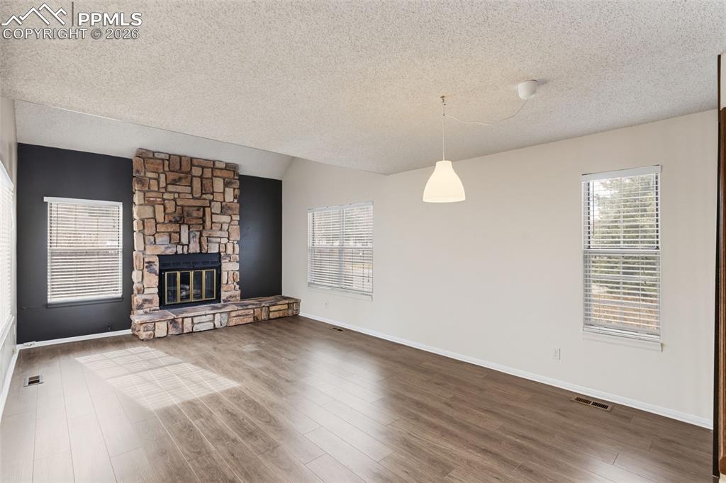 Image 10 of 47: Living room featuring wood-style floors and a stone fireplace