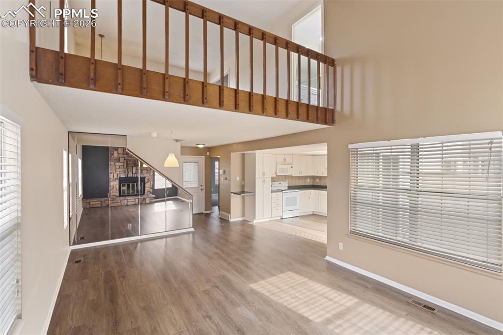 Image 14 of 47: Living room with light wood-type flooring, a stone fireplace, and a high ce
