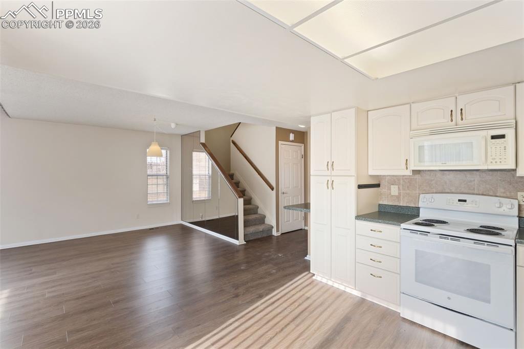 Image 15 of 47: Kitchen with white appliances, tasteful backsplash, wood-style floors, whit