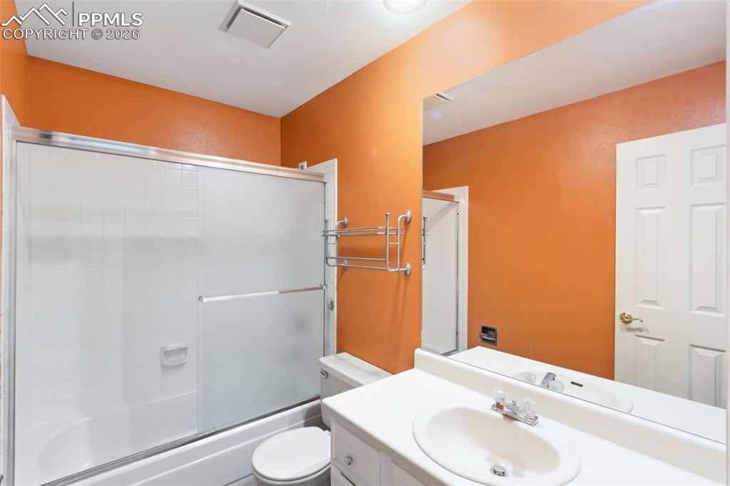 Image 35 of 47: Main-level bathroom with vanity and bath / shower combo with glass door