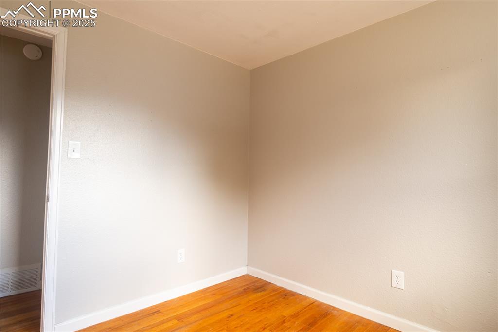 Image 12 of 44: Empty room with light wood-style floors and a smoke detector