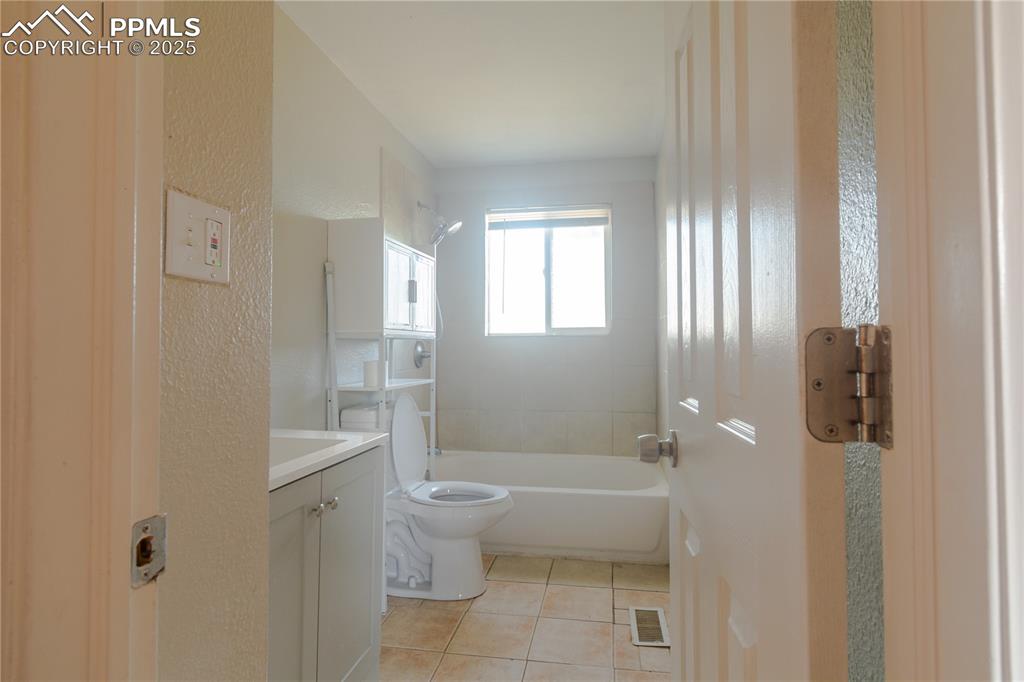 Image 23 of 44: Full bathroom with vanity, tile patterned floors, shower / washtub combinat