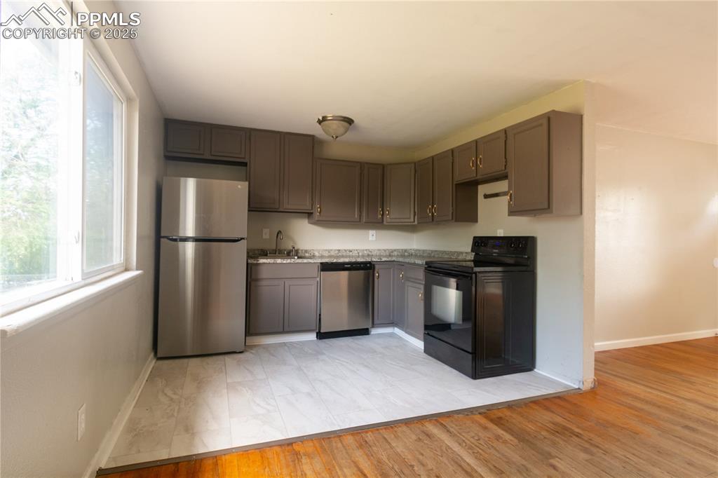 Image 8 of 44: Kitchen with appliances with stainless steel finishes, gray cabinets, light