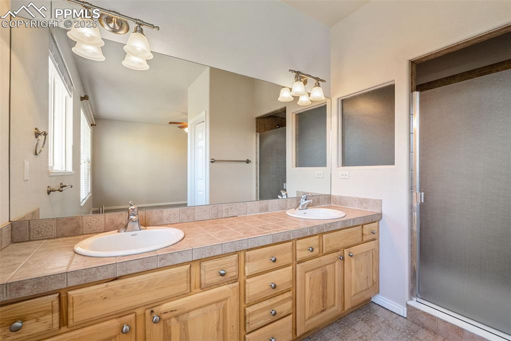 Image 14 of 50: Full bath featuring a stall shower, double vanity, and a chandelier