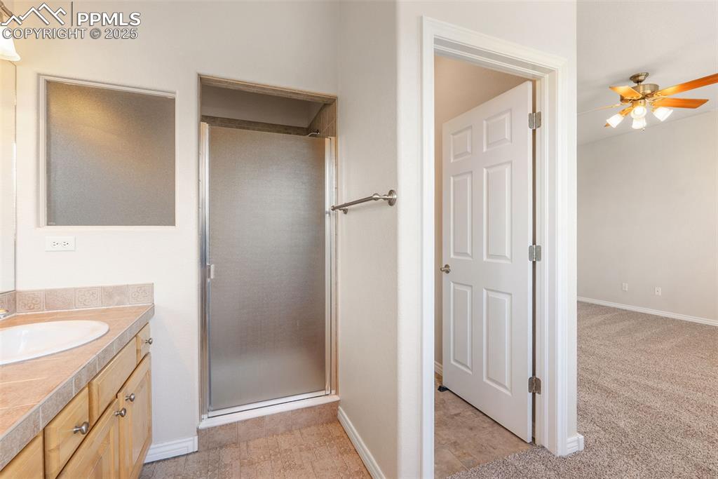 Image 15 of 50: Full bathroom with vanity, a shower stall, a ceiling fan, and light colored