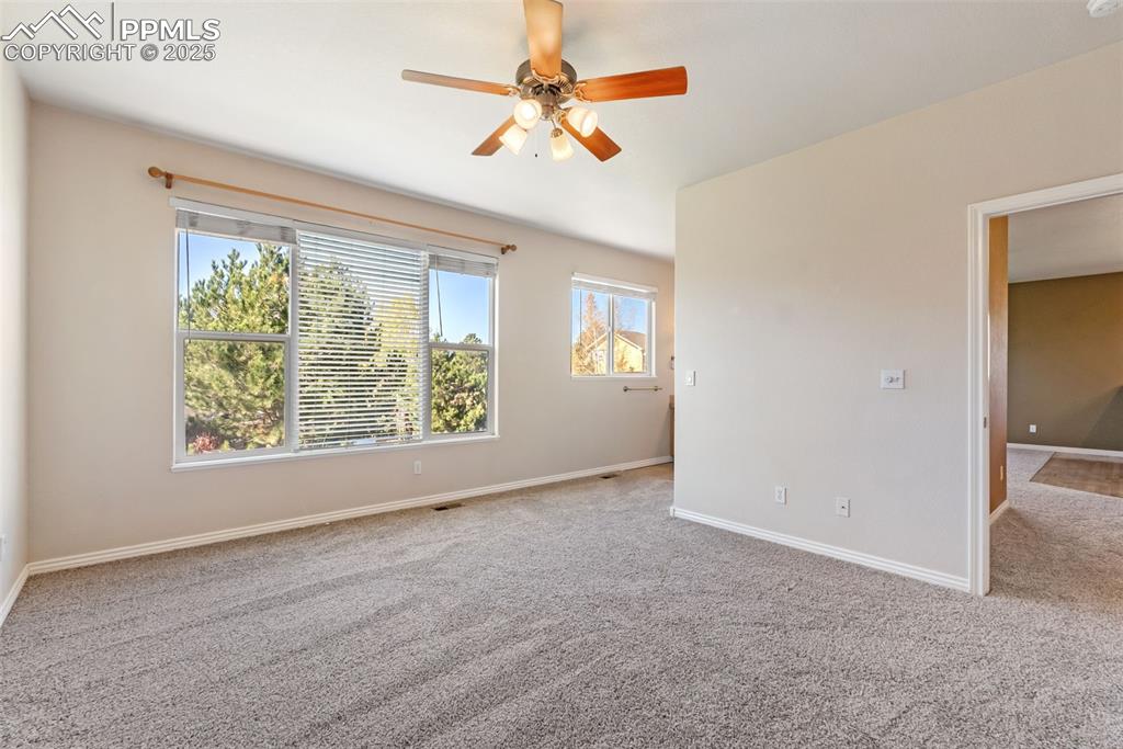 Image 17 of 50: Empty room featuring light colored carpet and a ceiling fan