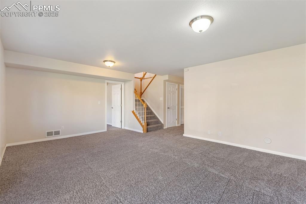 Image 27 of 50: Carpeted empty room featuring stairs and baseboards