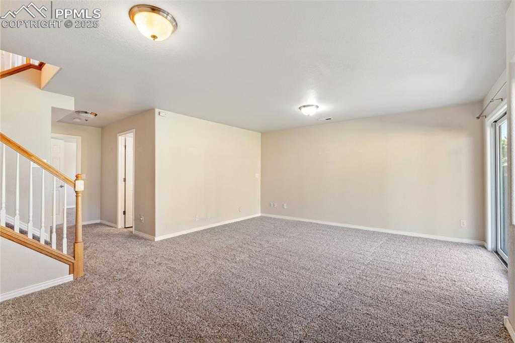 Image 28 of 50: Empty room with stairway and light carpet