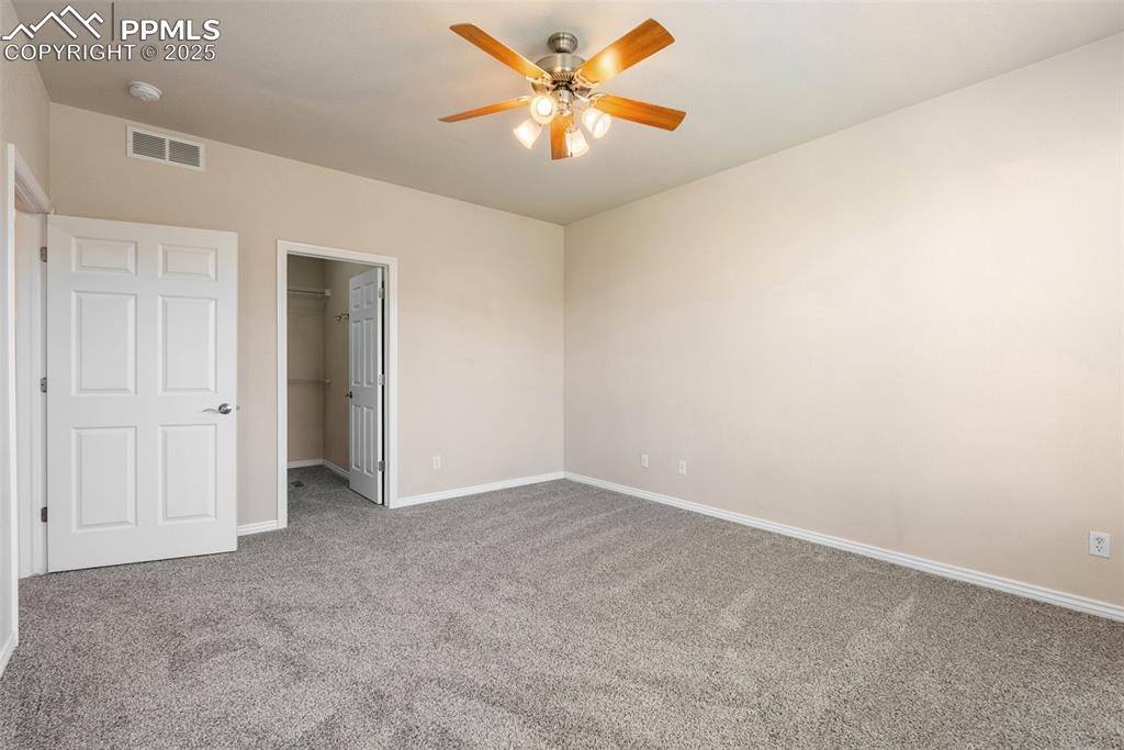 Image 32 of 50: Unfurnished bedroom with carpet, a spacious closet, and a ceiling fan
