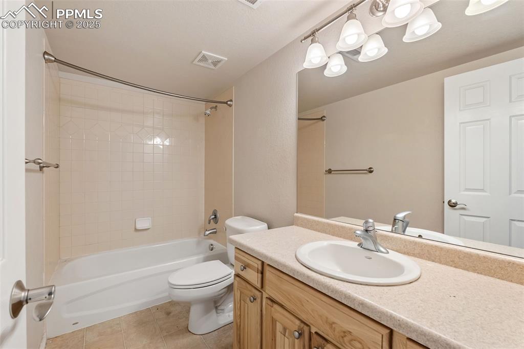 Image 35 of 50: Bathroom with washtub / shower combination, vanity, and light tile patterne