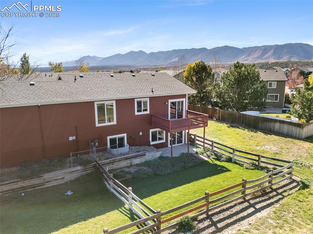Image 44 of 50: Rear view of house featuring a fenced backyard, a patio, a deck with mounta