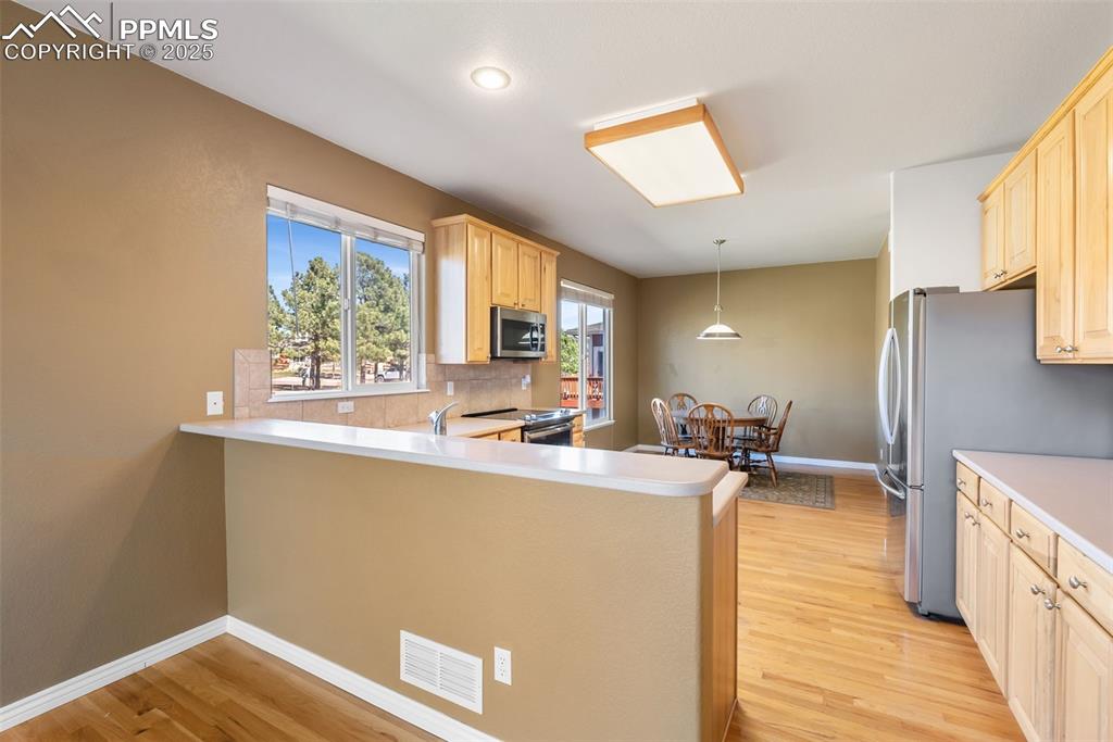 Image 8 of 50: Kitchen with light countertops, light brown cabinets, and light wood-type f