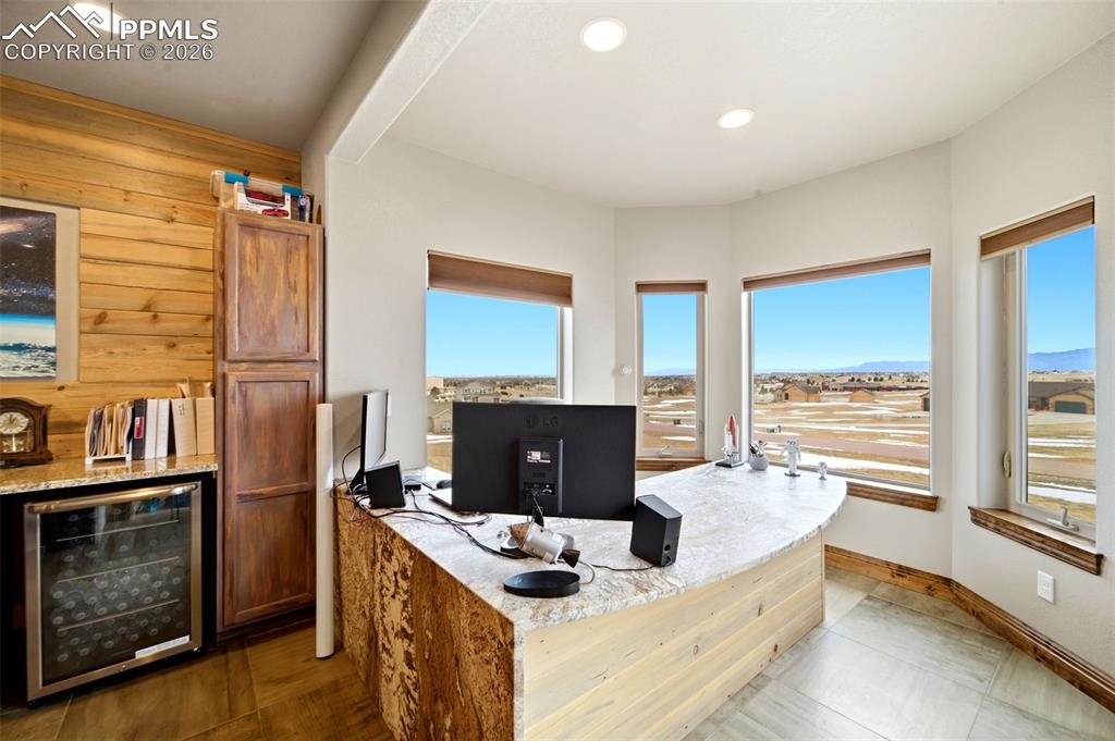 Image 12 of 48: Home office featuring wine cooler, recessed lighting, and wood walls