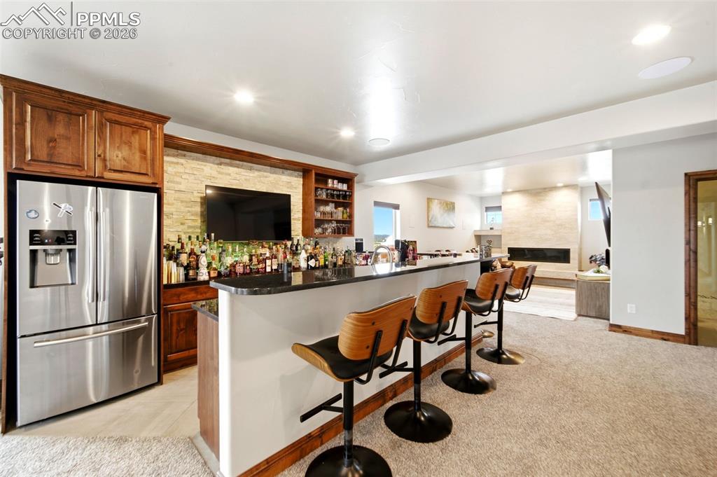 Image 13 of 48: Indoor dry bar featuring stainless steel fridge with ice dispenser, light c