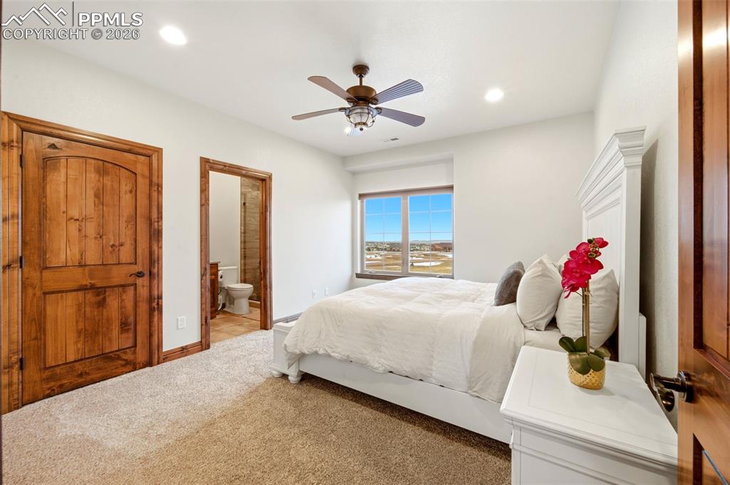 Image 25 of 48: Bedroom with a ceiling fan, ensuite bathroom, light carpet, and recessed li