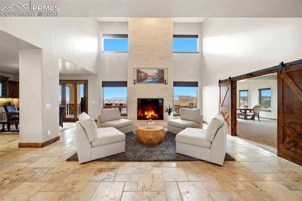 Image 8 of 48: Living room featuring a barn door, stone tile floors, a high ceiling, plent