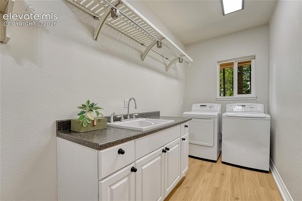 Image 23 of 49: Main level laundry with garage access, utility sink and window. Washer and