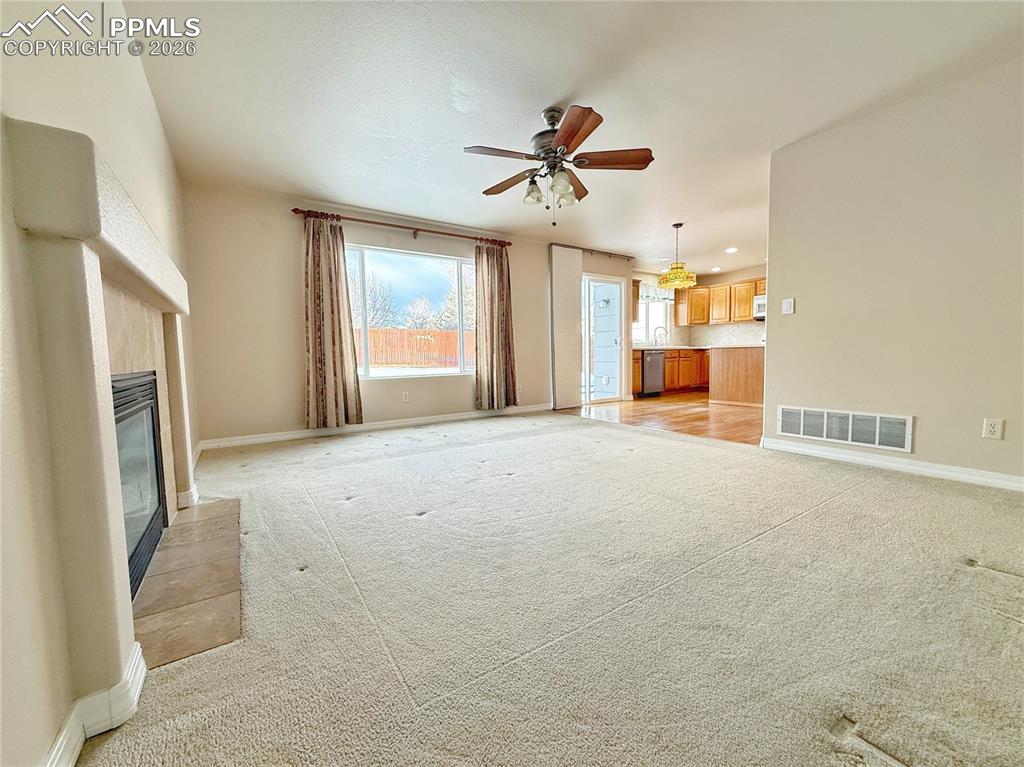 Image 9 of 28: Unfurnished living room with a fireplace, ceiling fan, light colored carpet