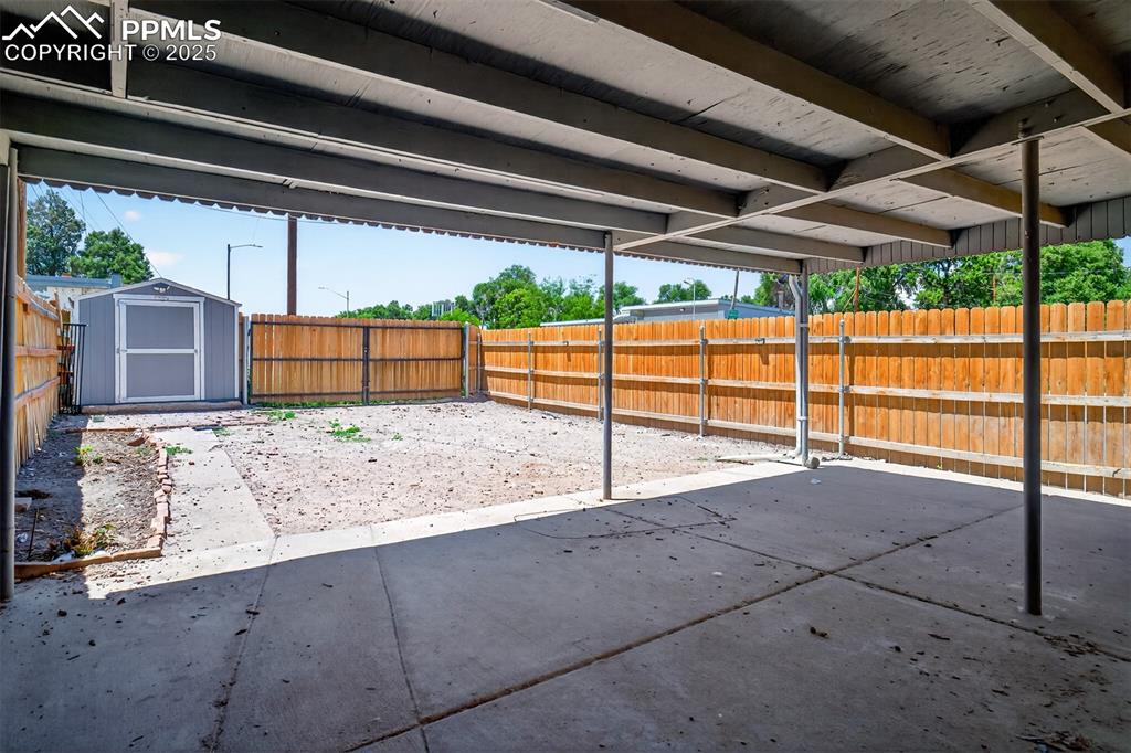 Image 16 of 20: Fenced backyard featuring a patio and a storage unit