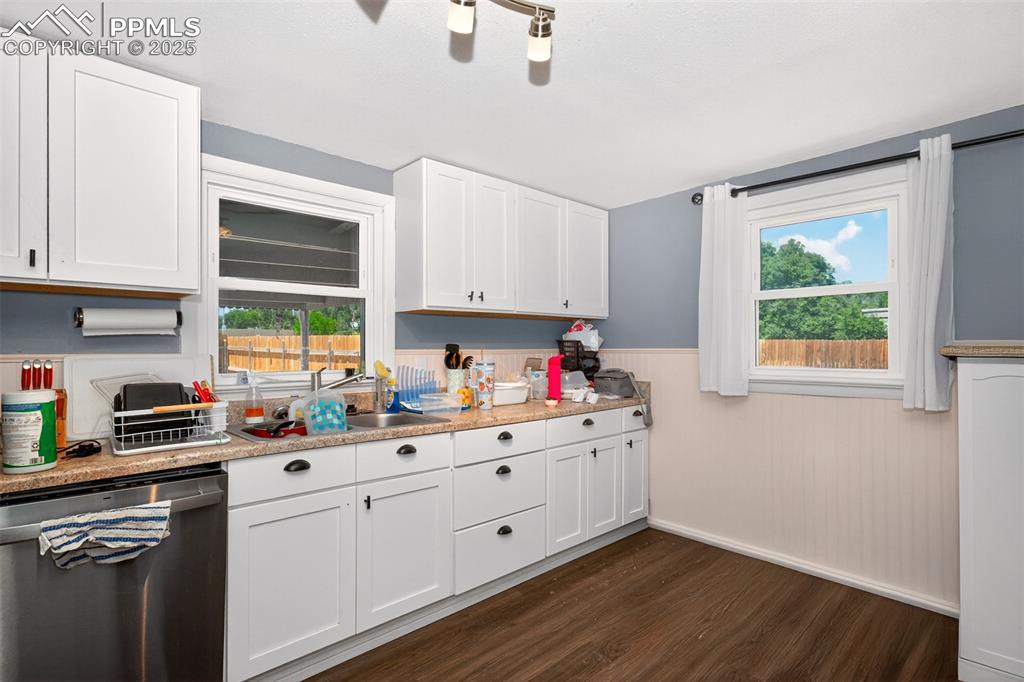 Image 3 of 20: Kitchen featuring dishwasher, dark wood finished floors, wainscoting, light