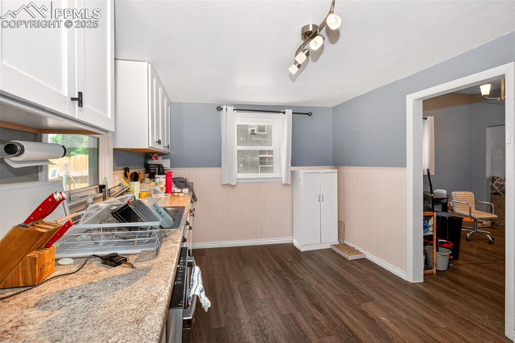 Image 4 of 20: Kitchen with dark wood finished floors, a wainscoted wall, white cabinetry,