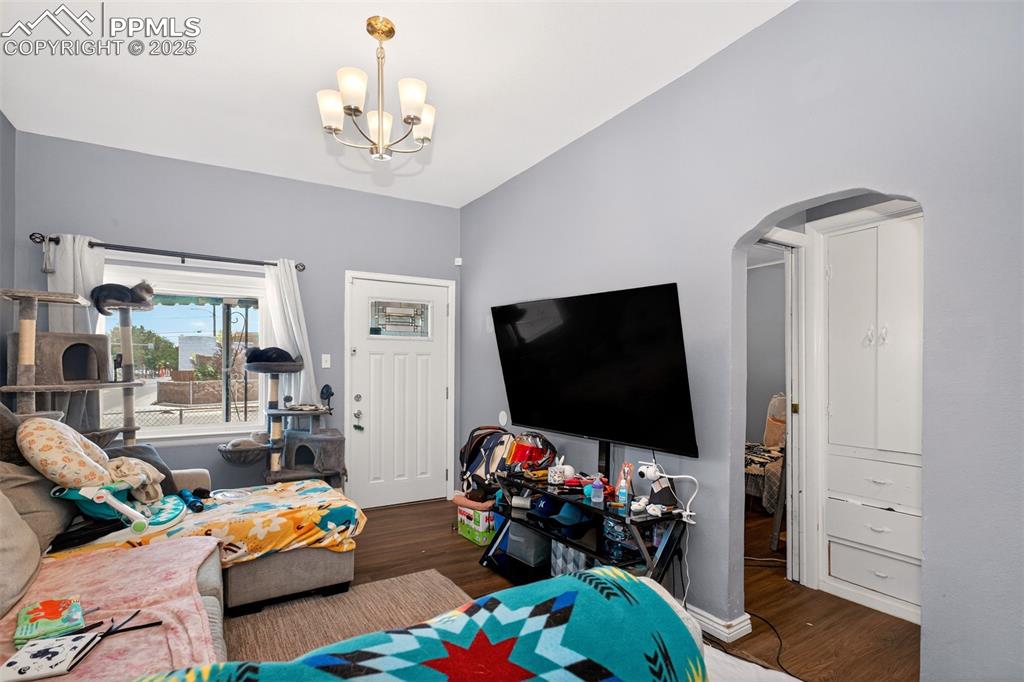 Image 8 of 20: Living room featuring arched walkways, a chandelier, and wood finished floo
