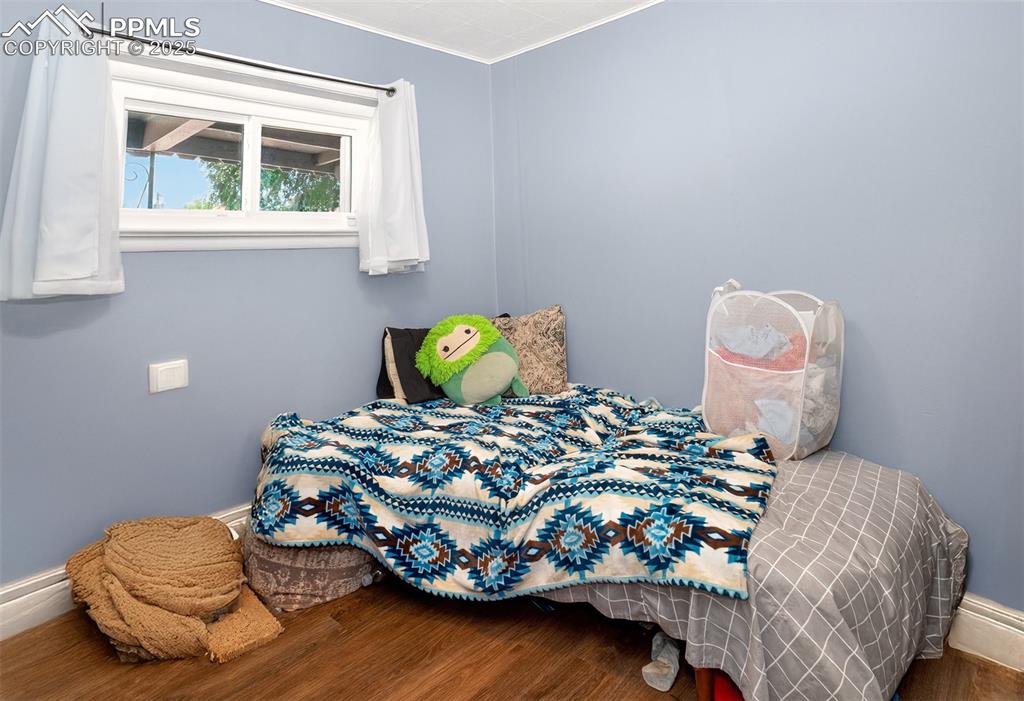 Image 9 of 20: Bedroom with wood finished floors and ornamental molding