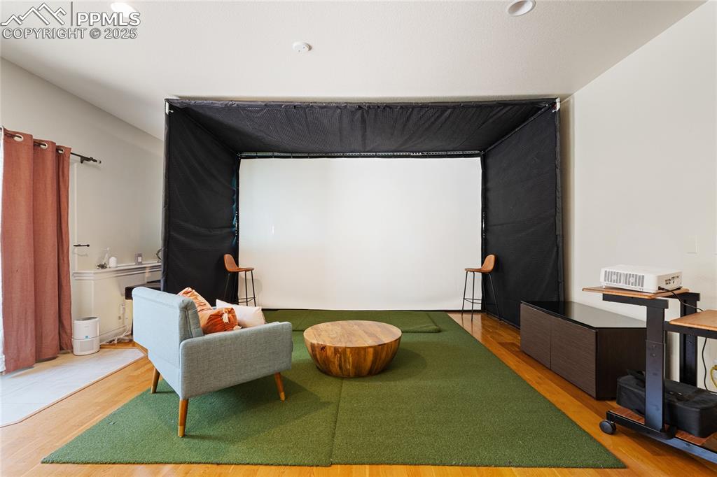 Image 30 of 46: Cinema with golf simulator, wood finished floors, and recessed lighting