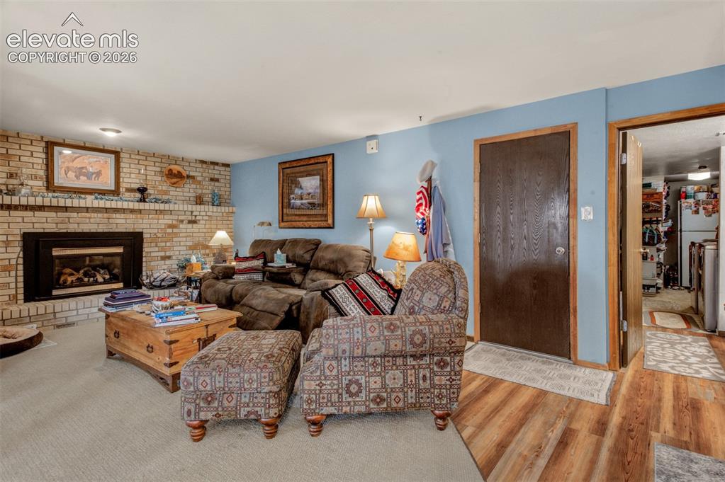 Image 10 of 45: Brick-faced fireplace with gas insert, door to garage, half bath, laundry a