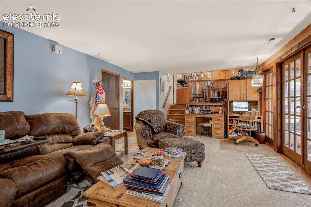 Image 11 of 45: Spacious Family room featuring wood-trimmed French doors opening to the sun