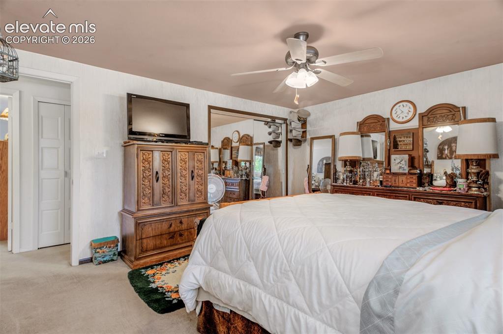 Image 17 of 45: Spacious primary bedroom featuring neutral carpet flooring, ceiling fan wit