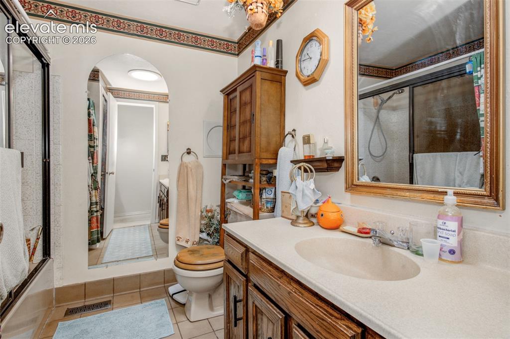 Image 20 of 45: Bathroom featuring a vanity with an integrated sink, framed mirror, and a b