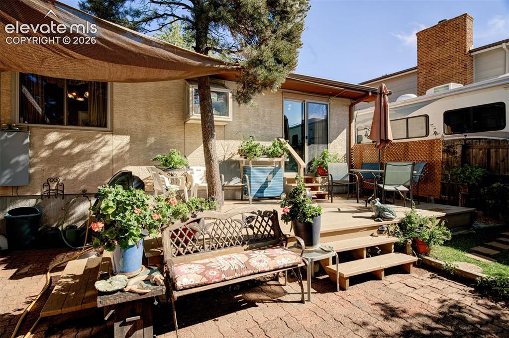 Image 31 of 45: Multi-level wood deck with steps, a sliding glass door, and an overhead sha