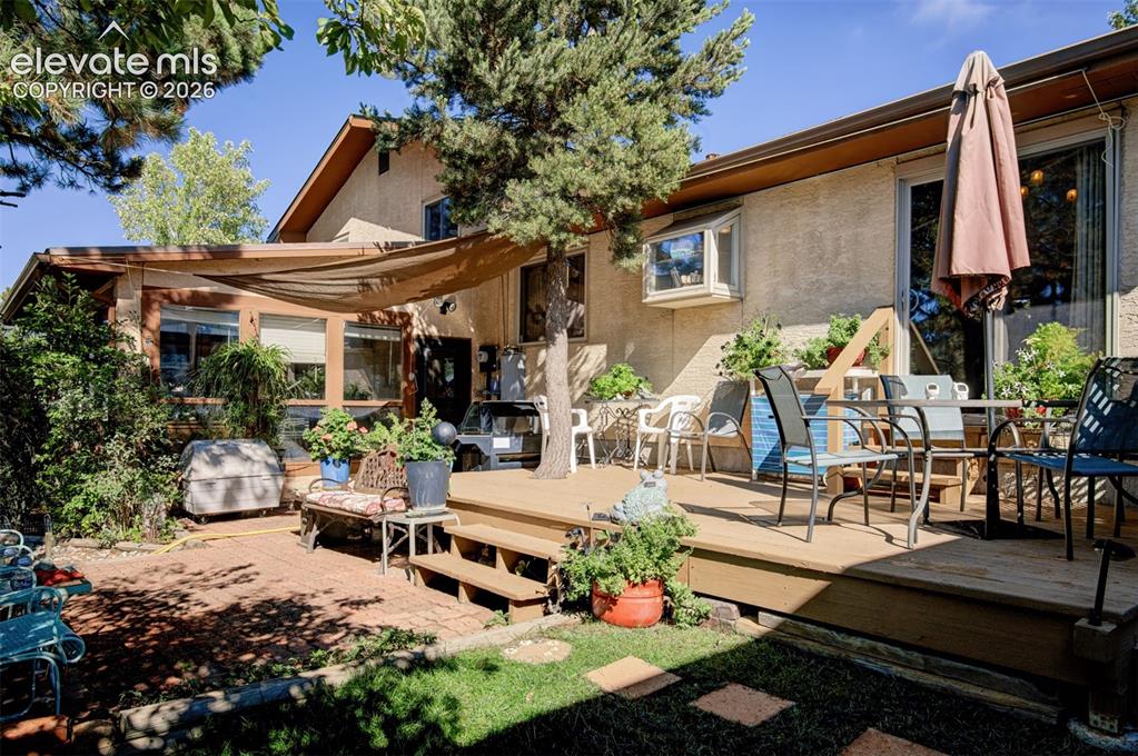 Image 32 of 45: Expansive outdoor living area featuring a multi-level wood deck, a brick pa