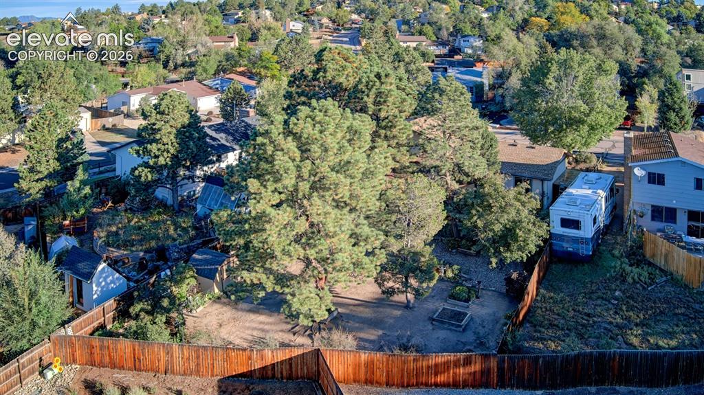Image 39 of 45: Extensive rear yard with a wood fence, mature trees, and a small shed struc
