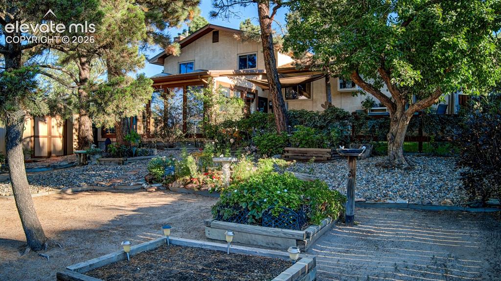 Image 40 of 45: Expansive exterior featuring mature trees, a sunroom with large windows, an