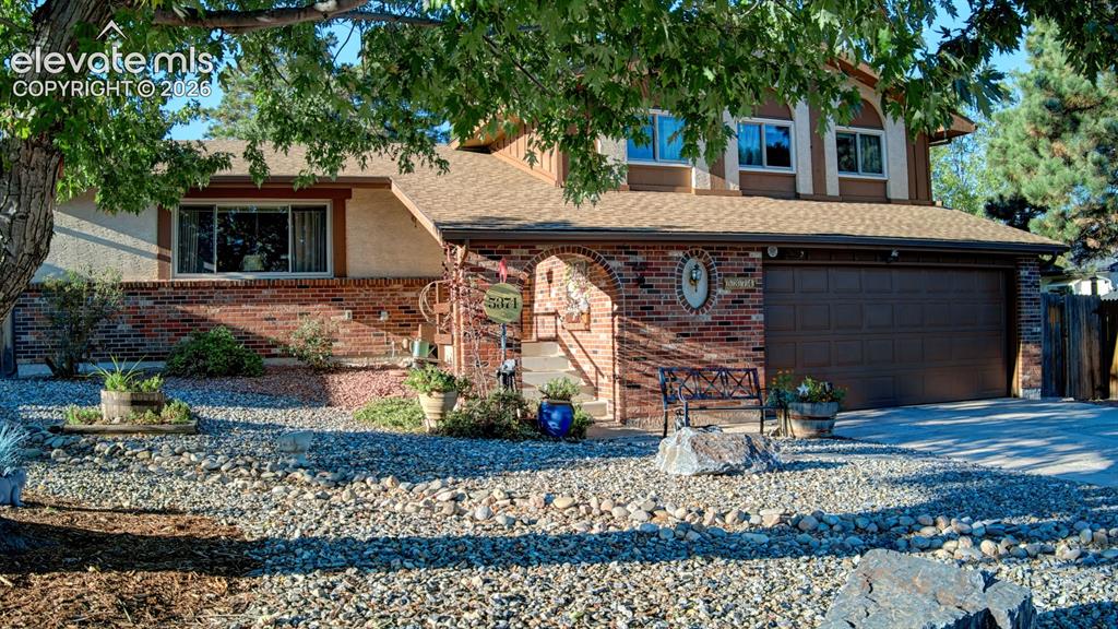 Image 41 of 45: Brick facade with arched entry, attached two-car garage, and upper-level wi