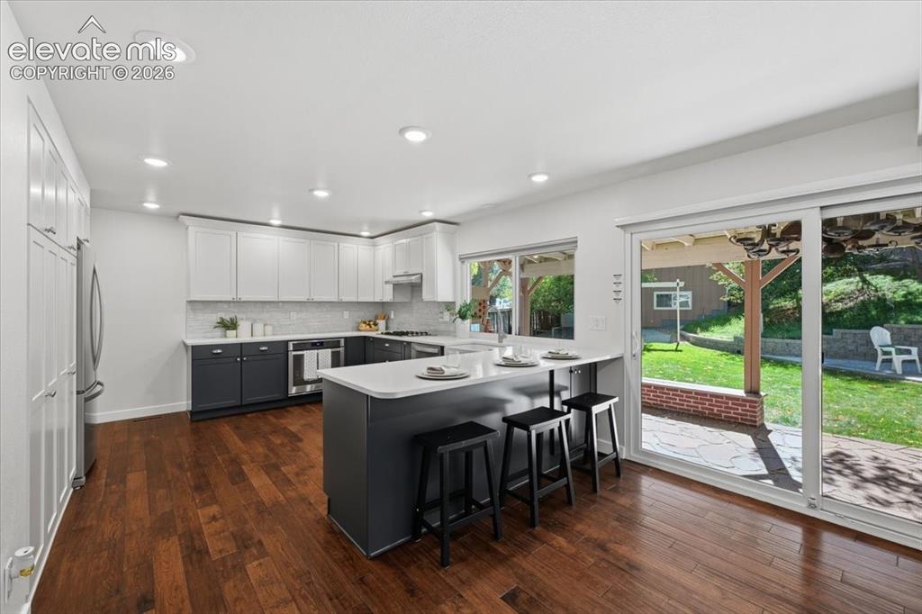 Image 15 of 50: Kitchen featuring wood flooring, two tone cabinetry, recessed lighting, a p