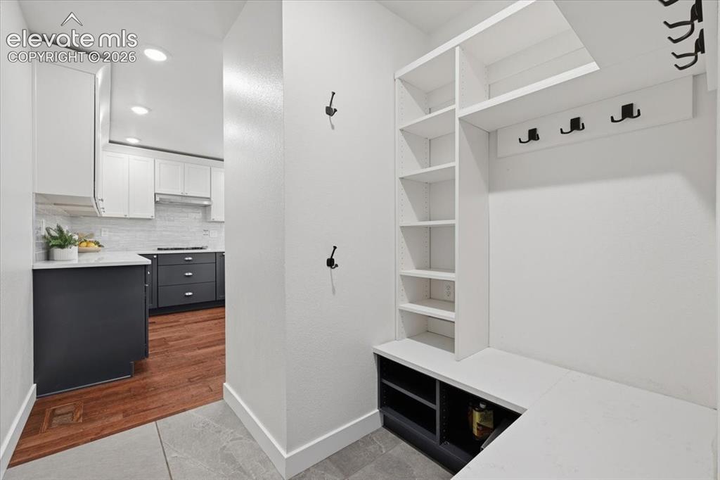 Image 21 of 50: Built-in entryway storage with shelving and bench seating with access from 