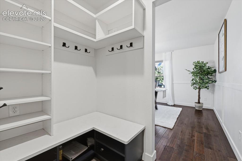 Image 22 of 50: Built in shelving with integrated hooks, dark wood flooring, and bright whi
